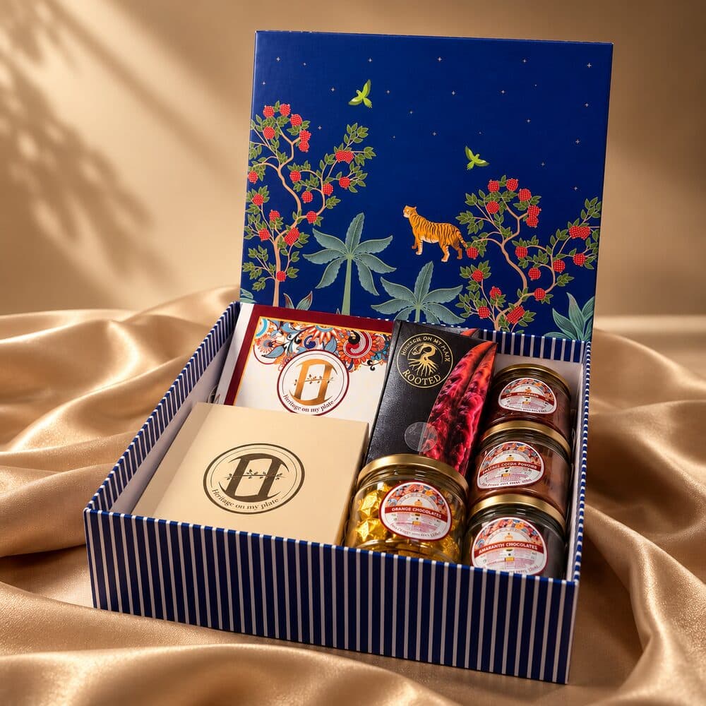 A blue and gold gift hamper with a ROOTED bar, chocolate jars and a heritage box