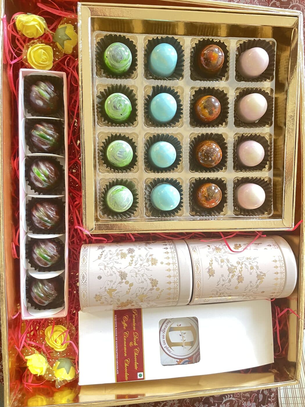 A gift box of painted chocolates with a row of truffles and a heritage tin