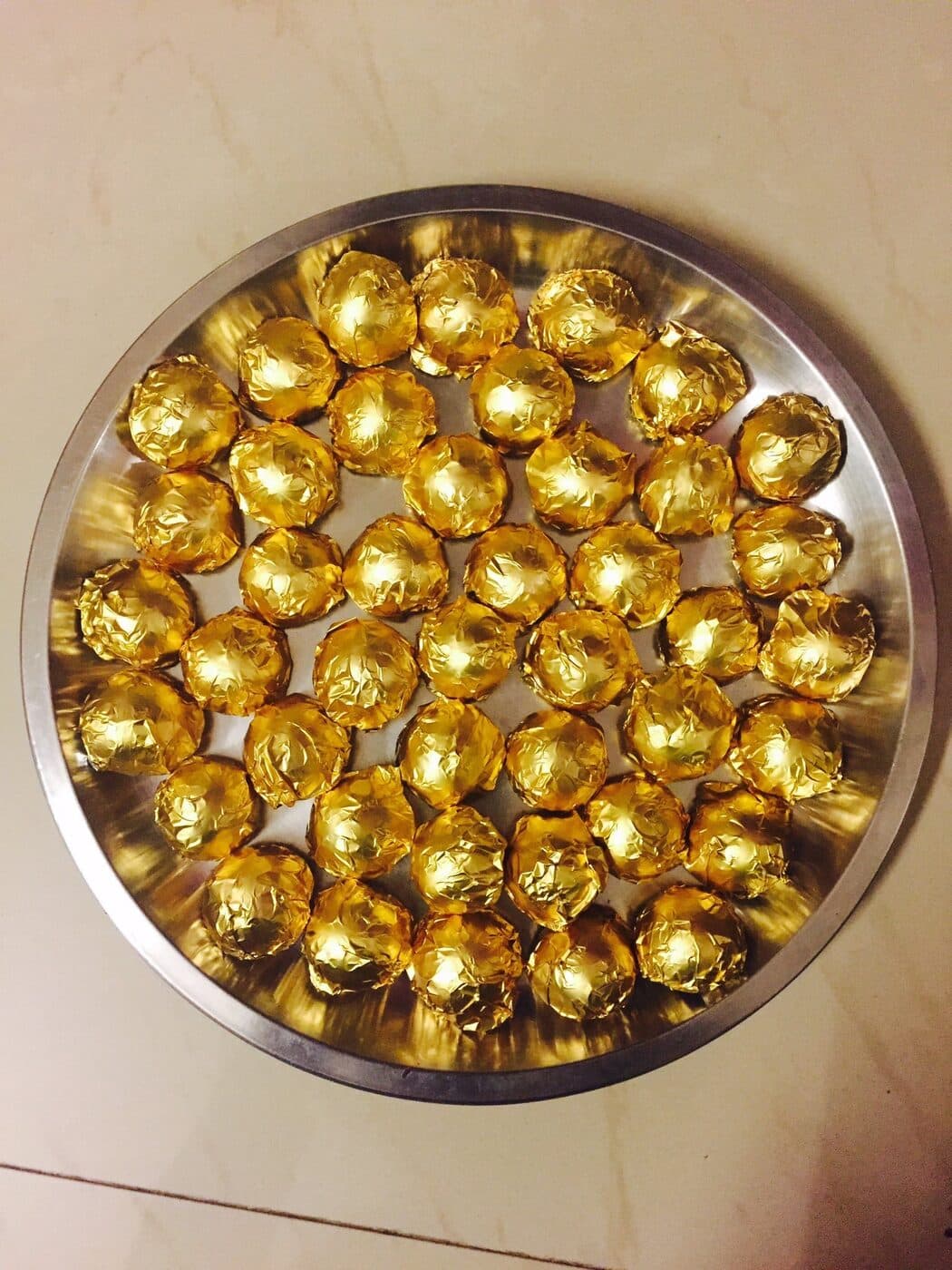 A steel thali full of chocolates wrapped in gold foil