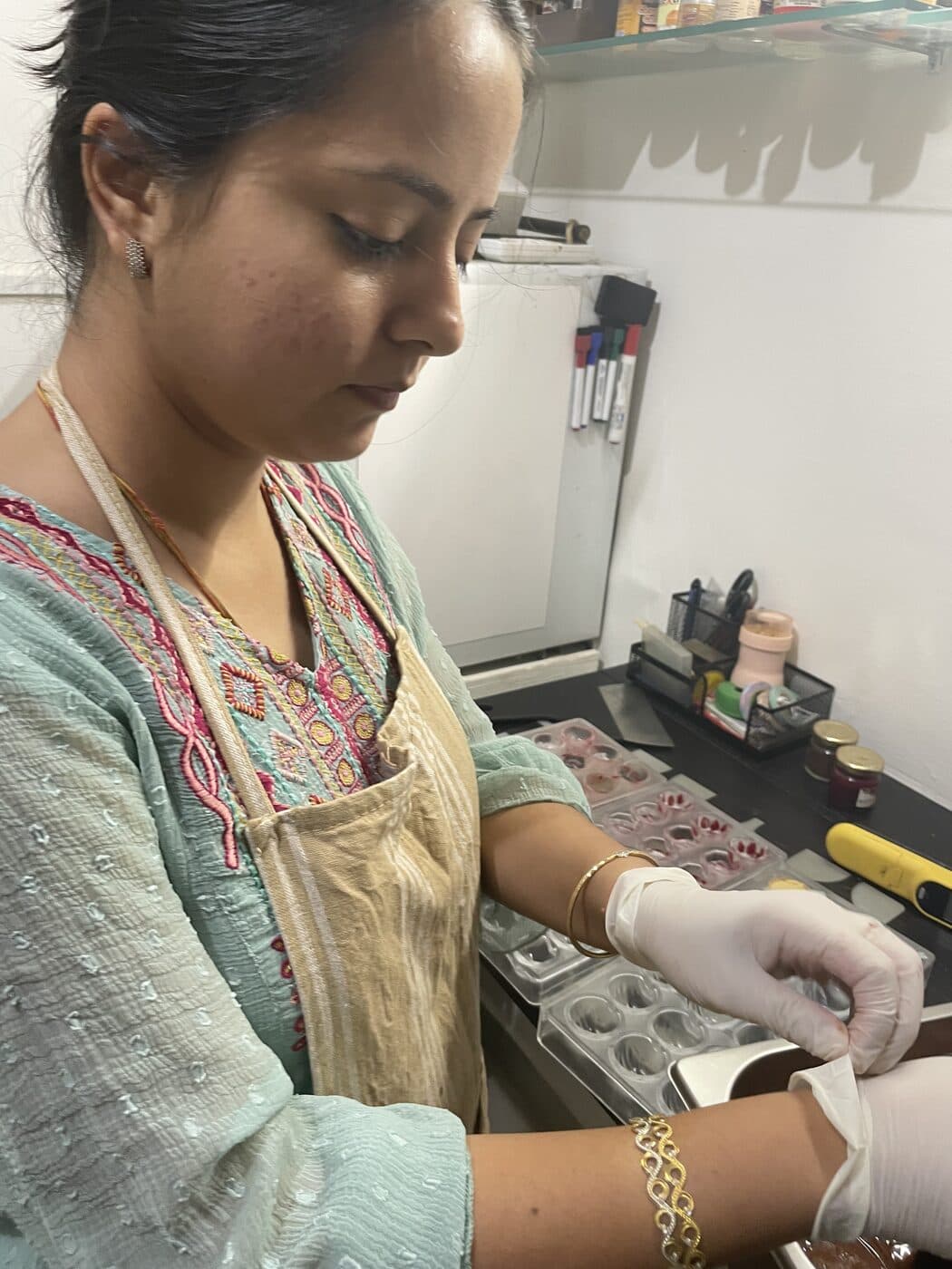 Sanchi, in gloves and an apron, making chocolates in our kitchen